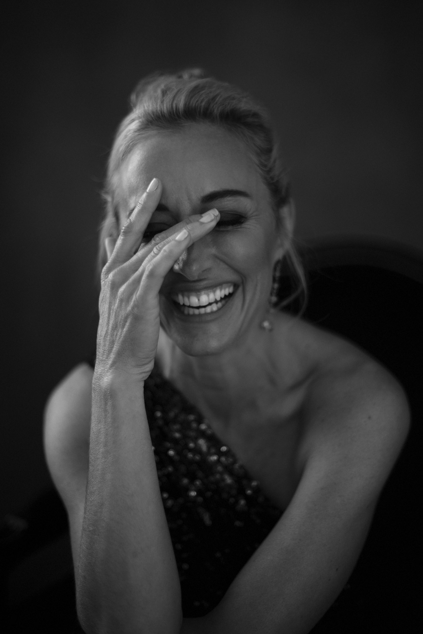 black and white image of woman laughing with her hand in front of her face